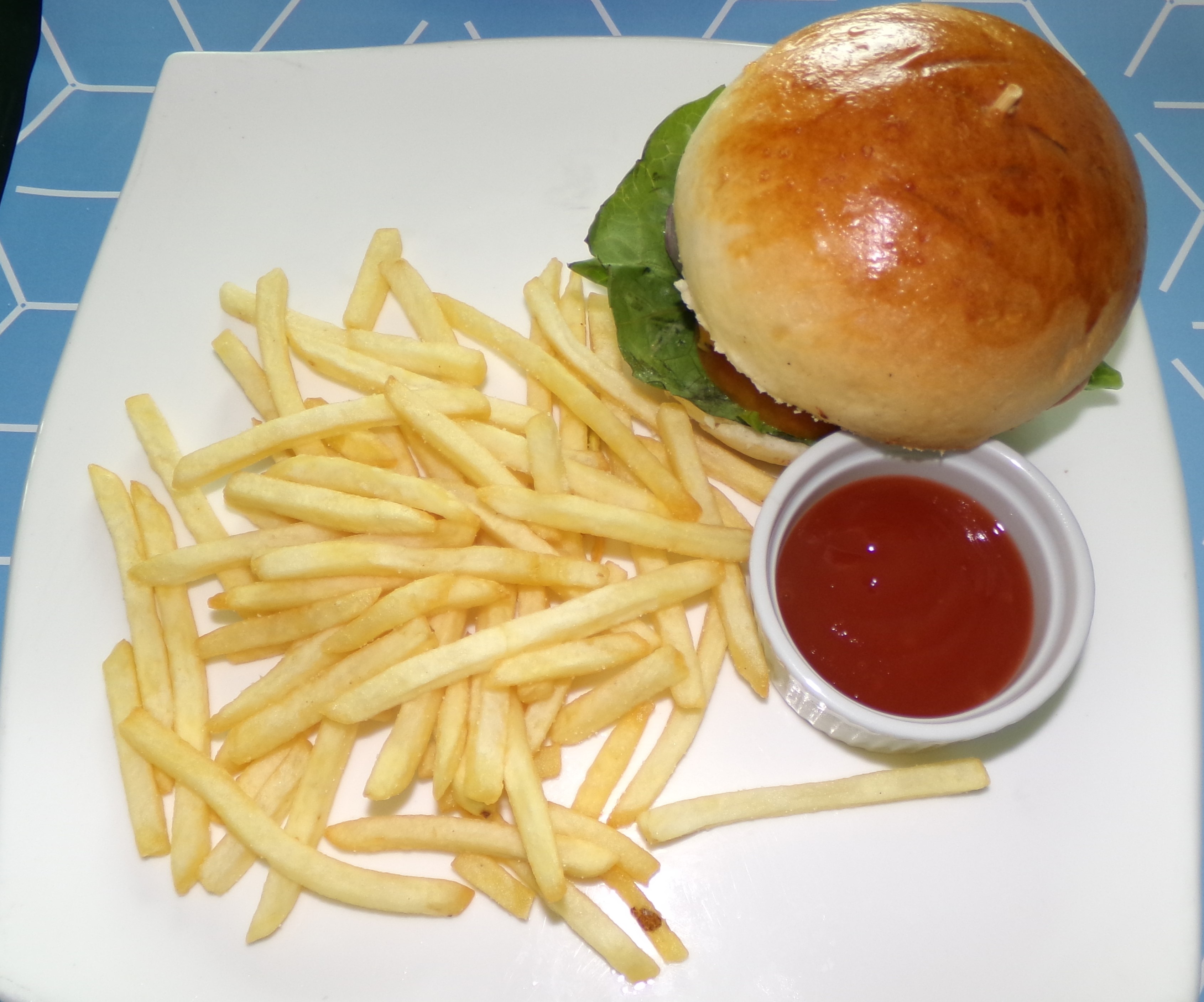 An image of a vegetarian burger with fries on the side on a white plate