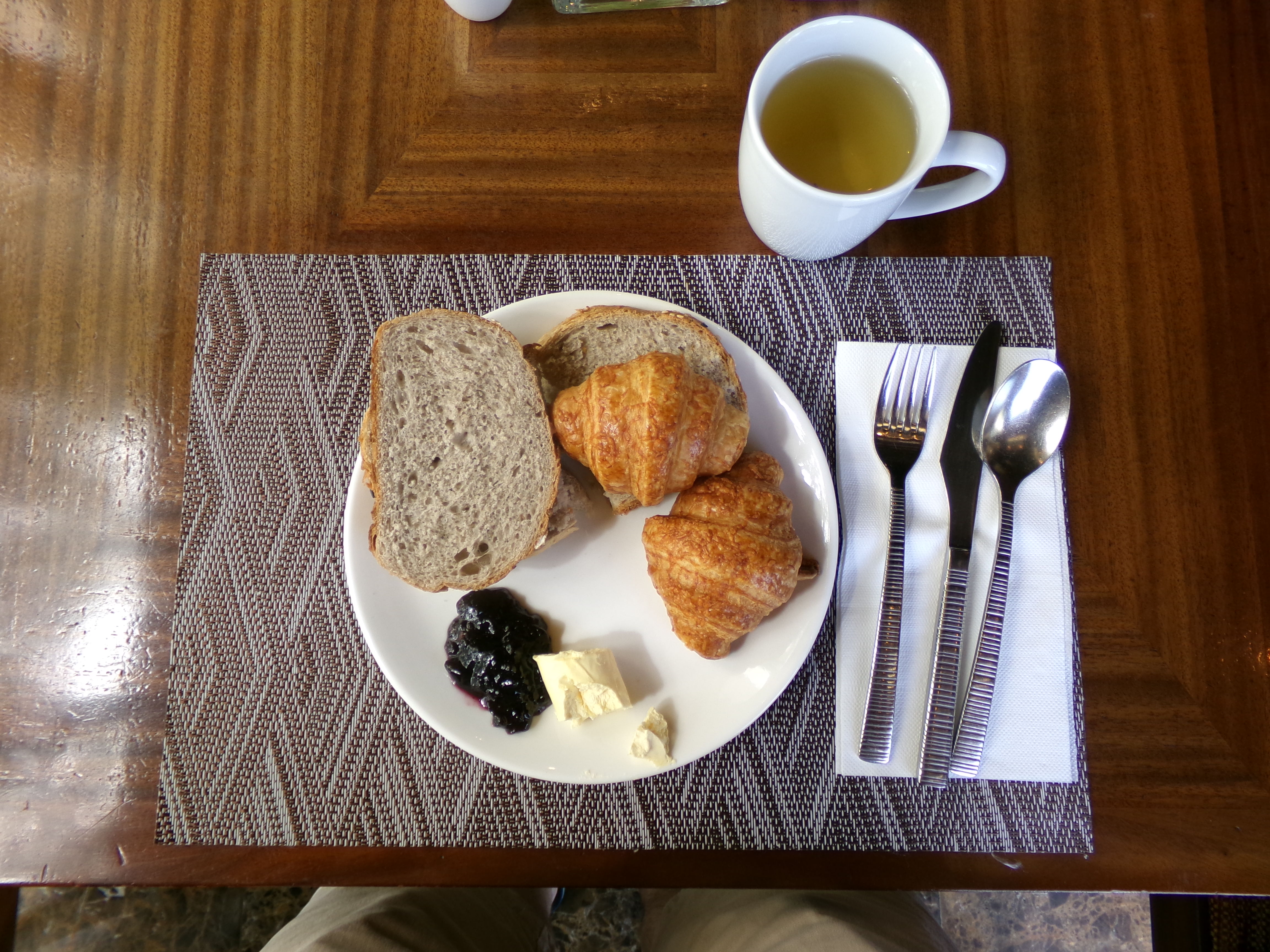 An image of cold breakfast with bread (croissant), butter and marmelade